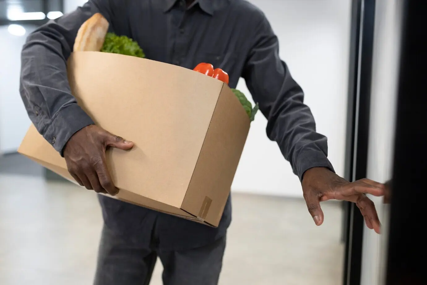 Мужчина, вид спереди, несёт коробку с продуктами.